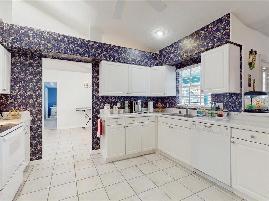 A kitchen with white cabinets, tiled countertops, and dark blue floral wallpaper — 2211 JESSICA LANE, KISSIMMEE, FL