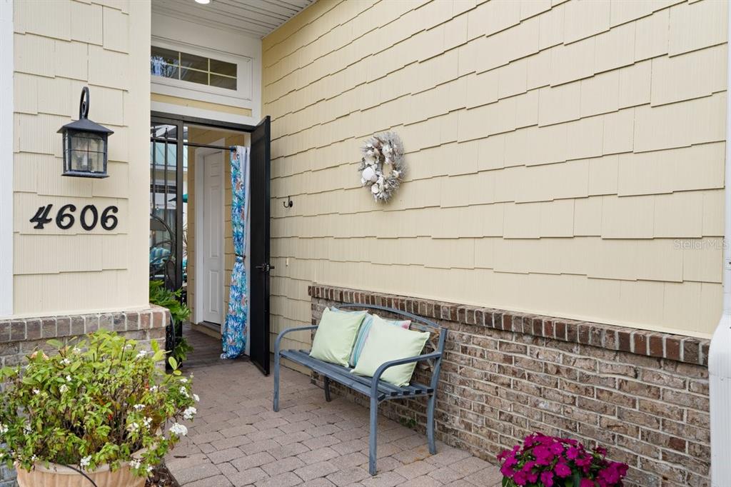 A paved entryway features a bench, a potted plant, and a house number on siding — 4606 OAK HAMMOCK COURT UNIT 4606, PONCE INLET, FL