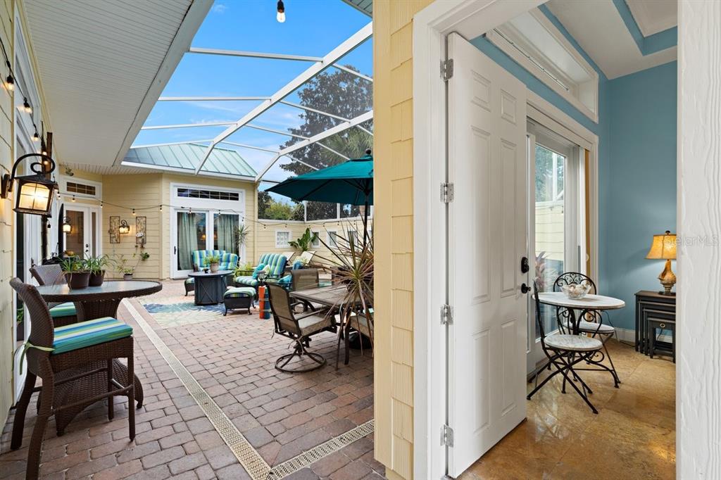 A screened-in patio with brick pavers, outdoor furniture, and an adjacent indoor seating area — 4606 OAK HAMMOCK COURT UNIT 4606, PONCE INLET, FL