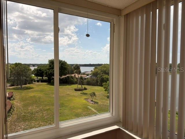 A view of a grassy yard and a lake through a large window with blinds — 700 MIRROR TERRACE NW UNIT 507, WINTER HAVEN, FL