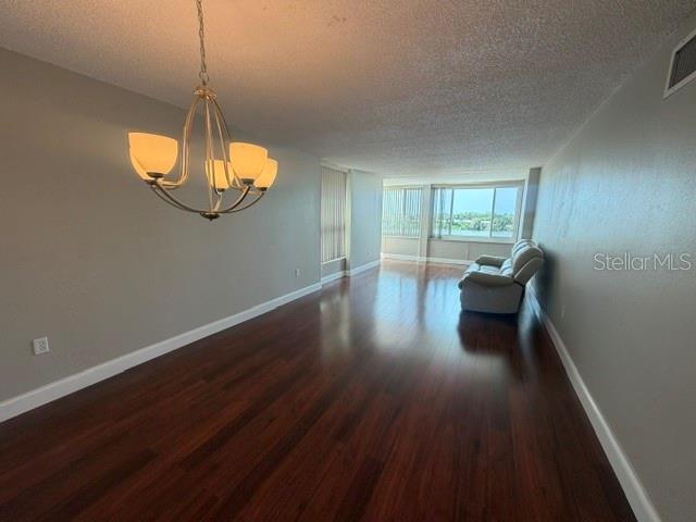 A living room features dark wood flooring, a chandelier, and a view of the water — 700 MIRROR TERRACE NW UNIT 507, WINTER HAVEN, FL