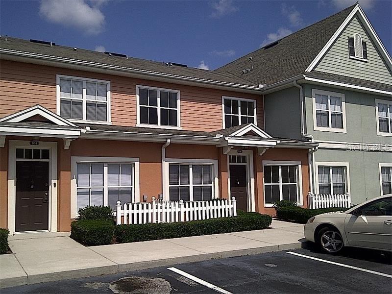 An exterior view of two-story townhomes with peach and green siding and white picket fences — 2219 SAN VITTORINO CIRCLE UNIT 106, KISSIMMEE, FL