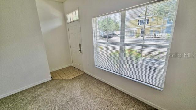 An interior view of a room with carpeted flooring, a white door, and a window — 2219 SAN VITTORINO CIRCLE UNIT 106, KISSIMMEE, FL