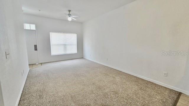An empty room with beige carpet, white walls, a ceiling fan, and a window — 2219 SAN VITTORINO CIRCLE UNIT 106, KISSIMMEE, FL