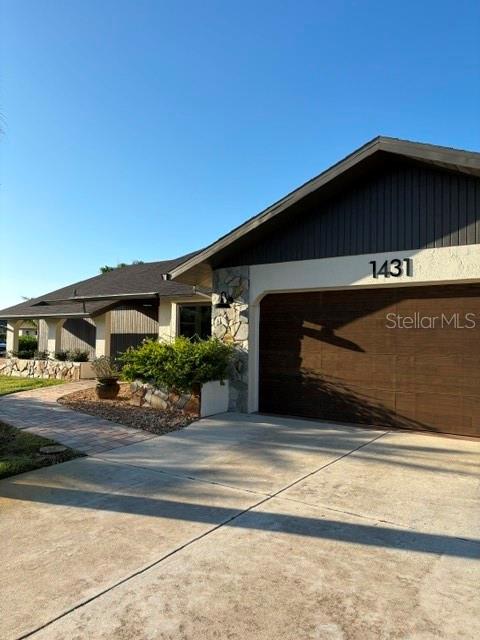 A single-story house features a brown garage door, stone accents, and a paved walkway — 1431 ROOSEVELT DRIVE, VENICE, FL
