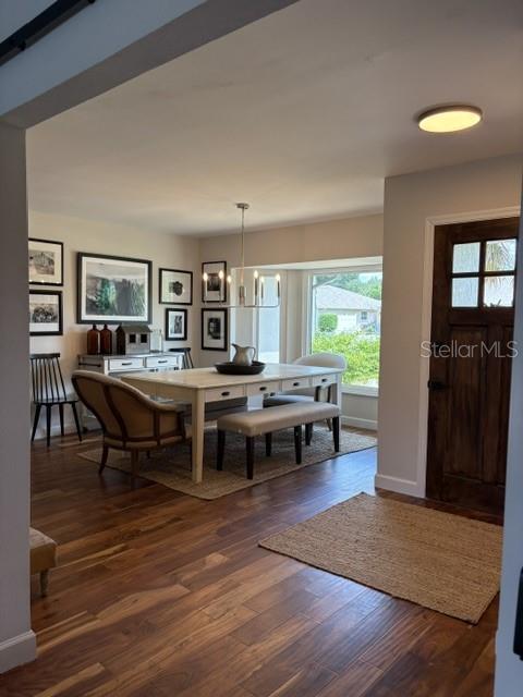 A dining room features a wooden table, chairs, a bench, and a dark wood door — 1431 ROOSEVELT DRIVE, VENICE, FL