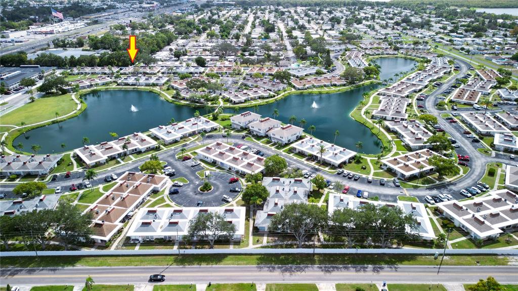An aerial view shows a residential community with multiple buildings surrounding a central lake — 4315 TAHITIAN GARDENS CIRCLE UNIT H, HOLIDAY, FL