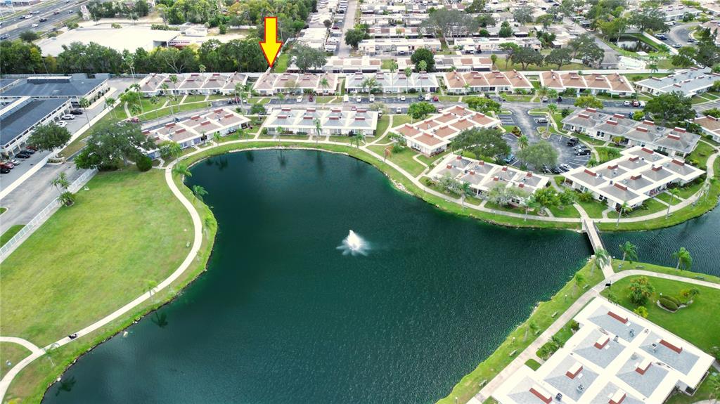 An aerial view shows a residential complex with multiple buildings surrounding a central lake — 4315 TAHITIAN GARDENS CIRCLE UNIT H, HOLIDAY, FL