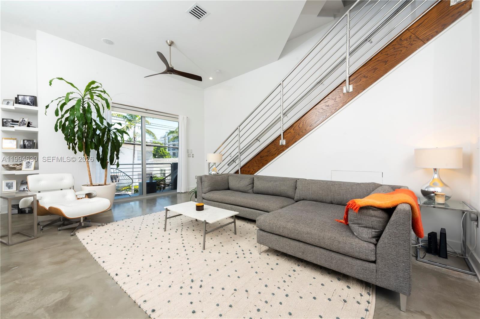 A living room features a grey sectional sofa, white lounge chair, and a staircase — 361 Jefferson Ave # 3, Miami Beach FL 33139, MIAMI BEACH, FL