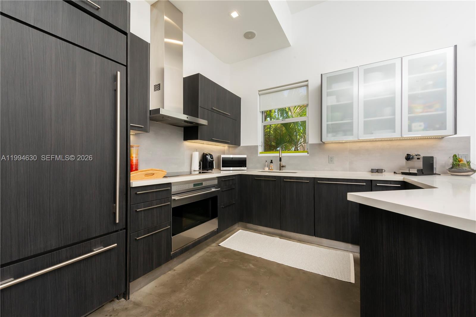 A modern kitchen features dark wood cabinetry, stainless steel appliances, and white countertops — 361 Jefferson Ave # 3, Miami Beach FL 33139, MIAMI BEACH, FL