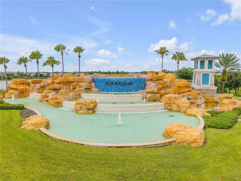 A large tiered stone fountain with blue tile accents sits in a landscaped community park — 9605 LOST CREEK DRIVE, WINTER GARDEN, FL