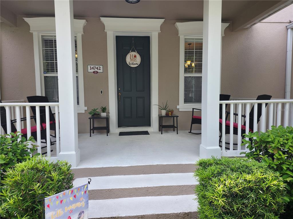 A covered front porch features a dark door, white columns, and two pairs of rocking chairs — 14742 CLARKSON DRIVE, ORLANDO, FL