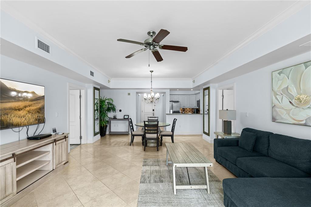 A living and dining area with tile floors, a dark sofa, and a ceiling fan — 7593 GATHERING DRIVE UNIT 706, KISSIMMEE, FL