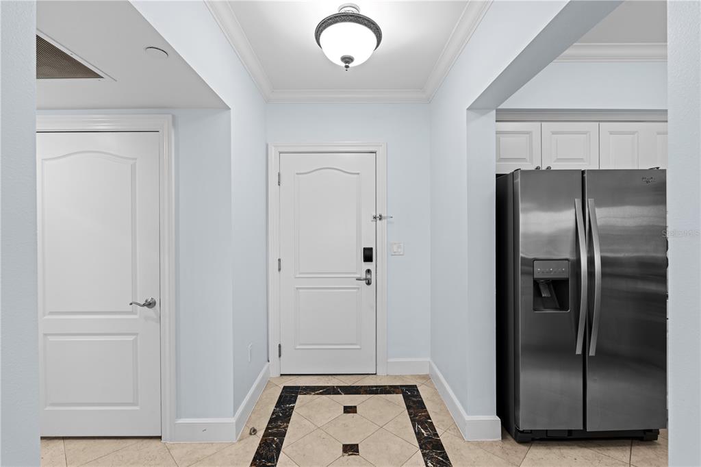 An entryway features a white door, tile flooring with a dark border, and a stainless refrigerator — 7593 GATHERING DRIVE UNIT 706, KISSIMMEE, FL