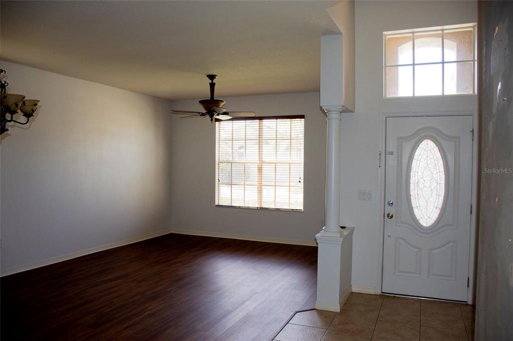 An empty room with wood-look flooring, a ceiling fan, and a white front door — 2504 LADOGA DRIVE, LAKELAND, FL