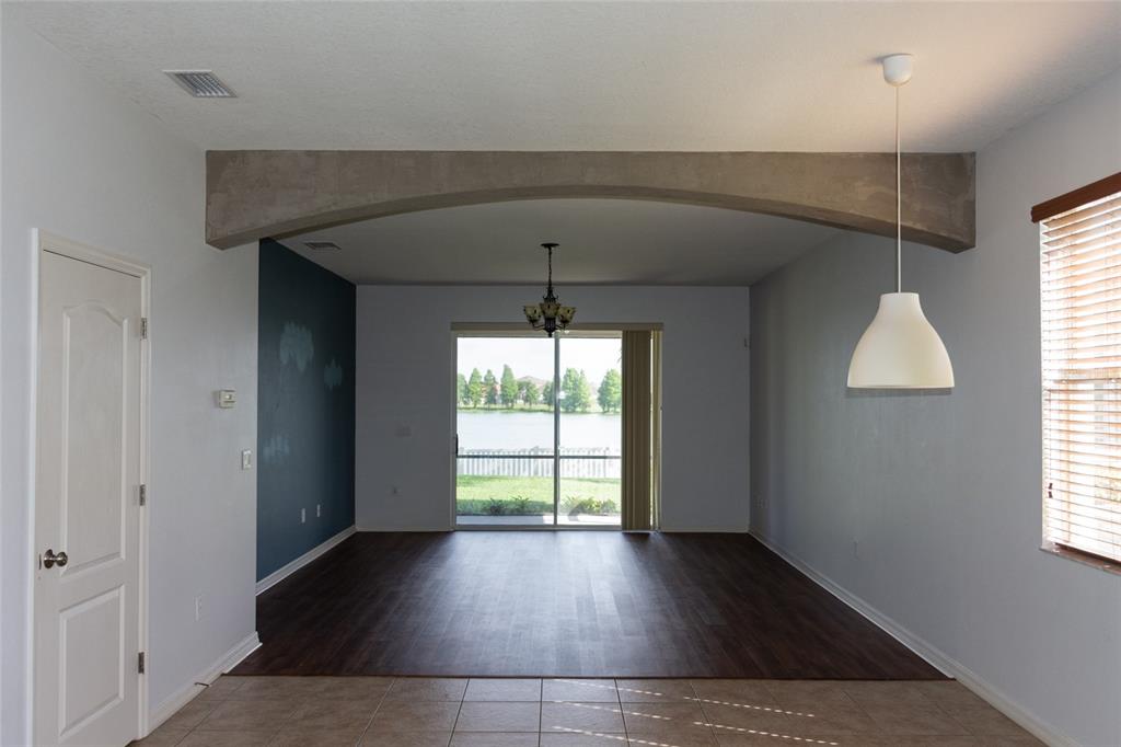An interior view of a living area with an arched entryway, dark flooring, and lake views — 2504 LADOGA DRIVE, LAKELAND, FL