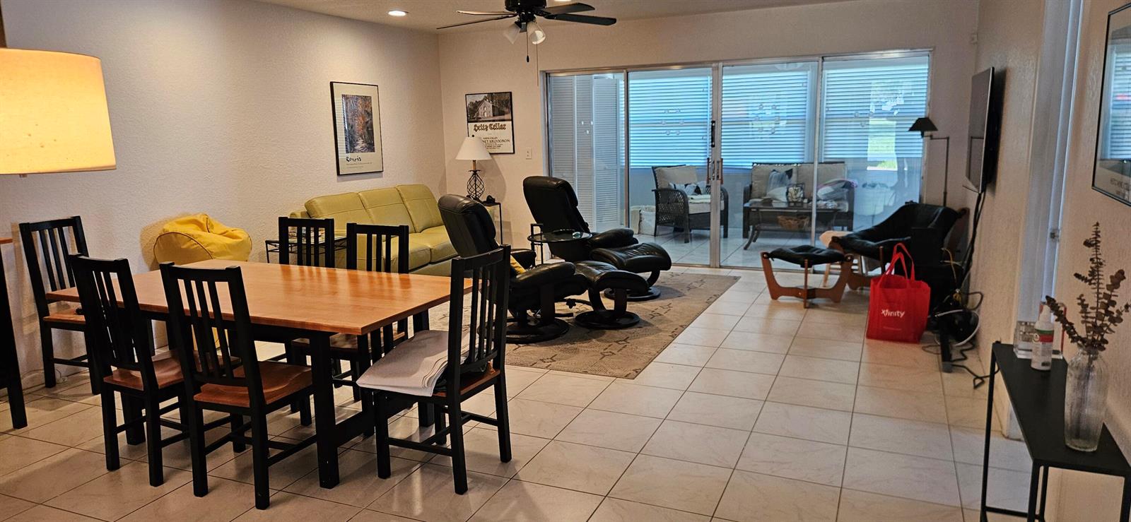 A dining area with a wooden table and chairs opens into a living room with recliners — 5432 Privet Pl Place # D, Delray Beach FL 33484, DELRAY BEACH, FL