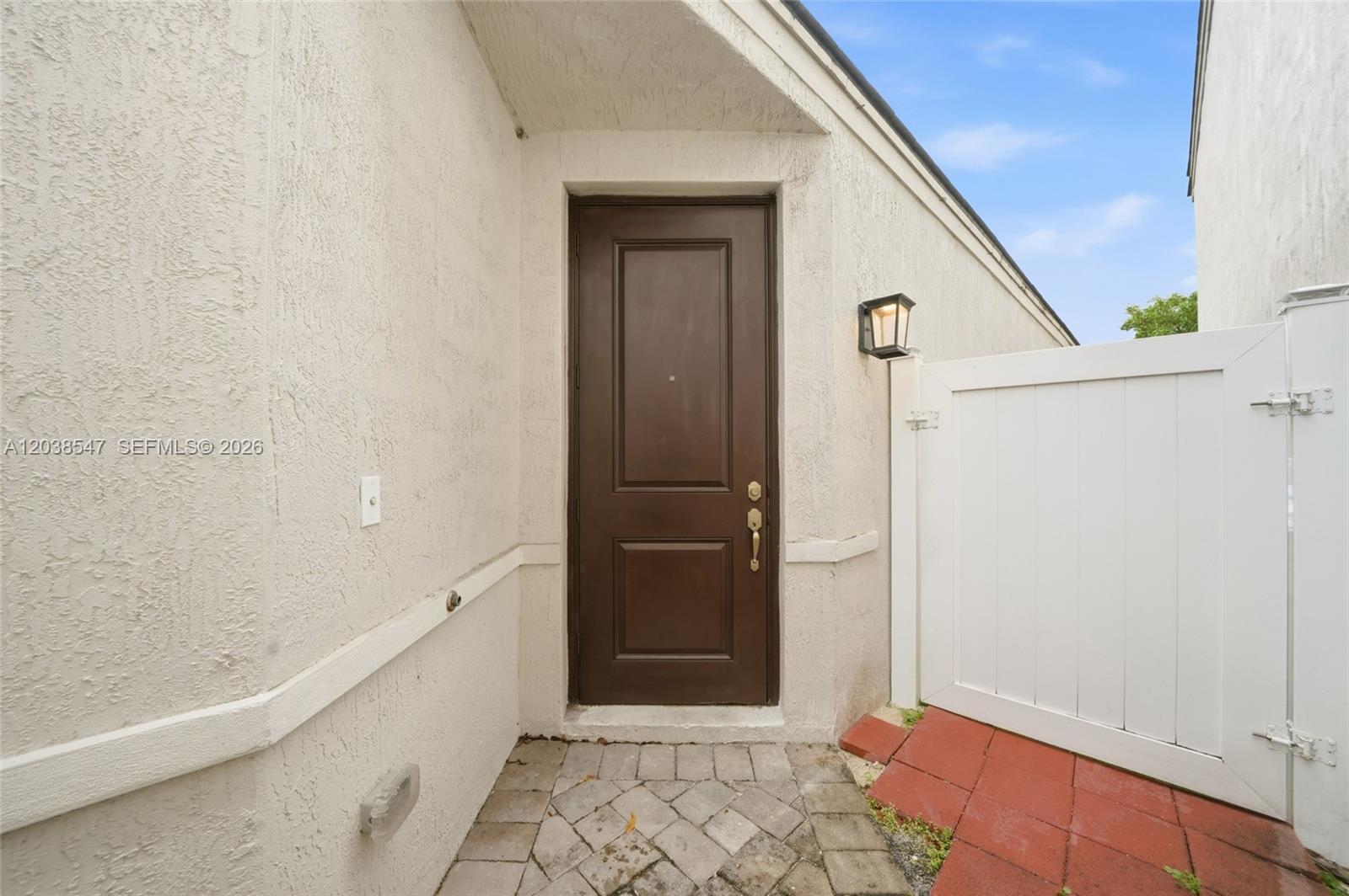 A brown door is set within a stucco entryway beside a white vinyl gate — 3384 NW 5th St, Pompano Beach FL 33069, POMPANO BEACH, FL