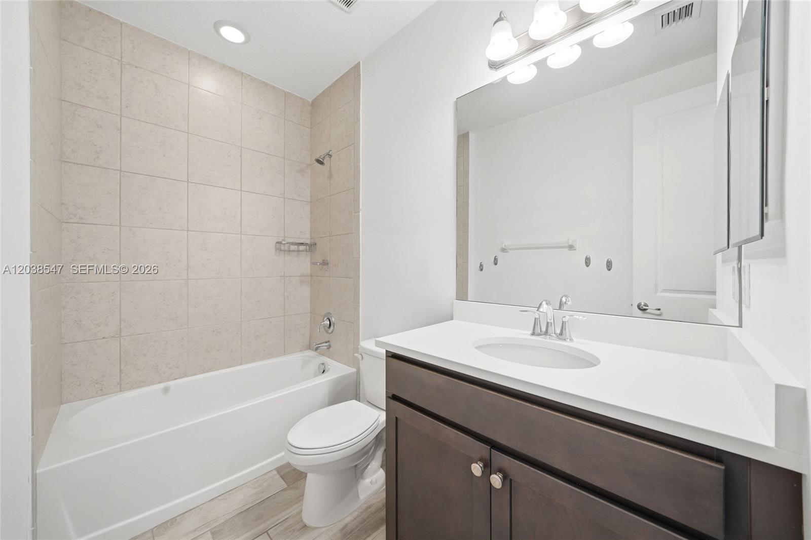 A bathroom features a tub-shower combo with beige tiles, a white vanity, and a toilet — 3384 NW 5th St, Pompano Beach FL 33069, POMPANO BEACH, FL
