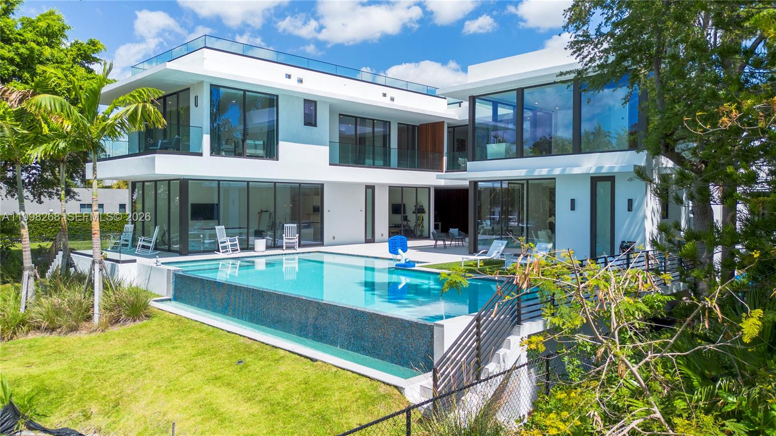 A modern two-story white house features a large infinity pool and glass-walled living spaces — 922 NE 78th St, Miami FL 33138, MIAMI, FL