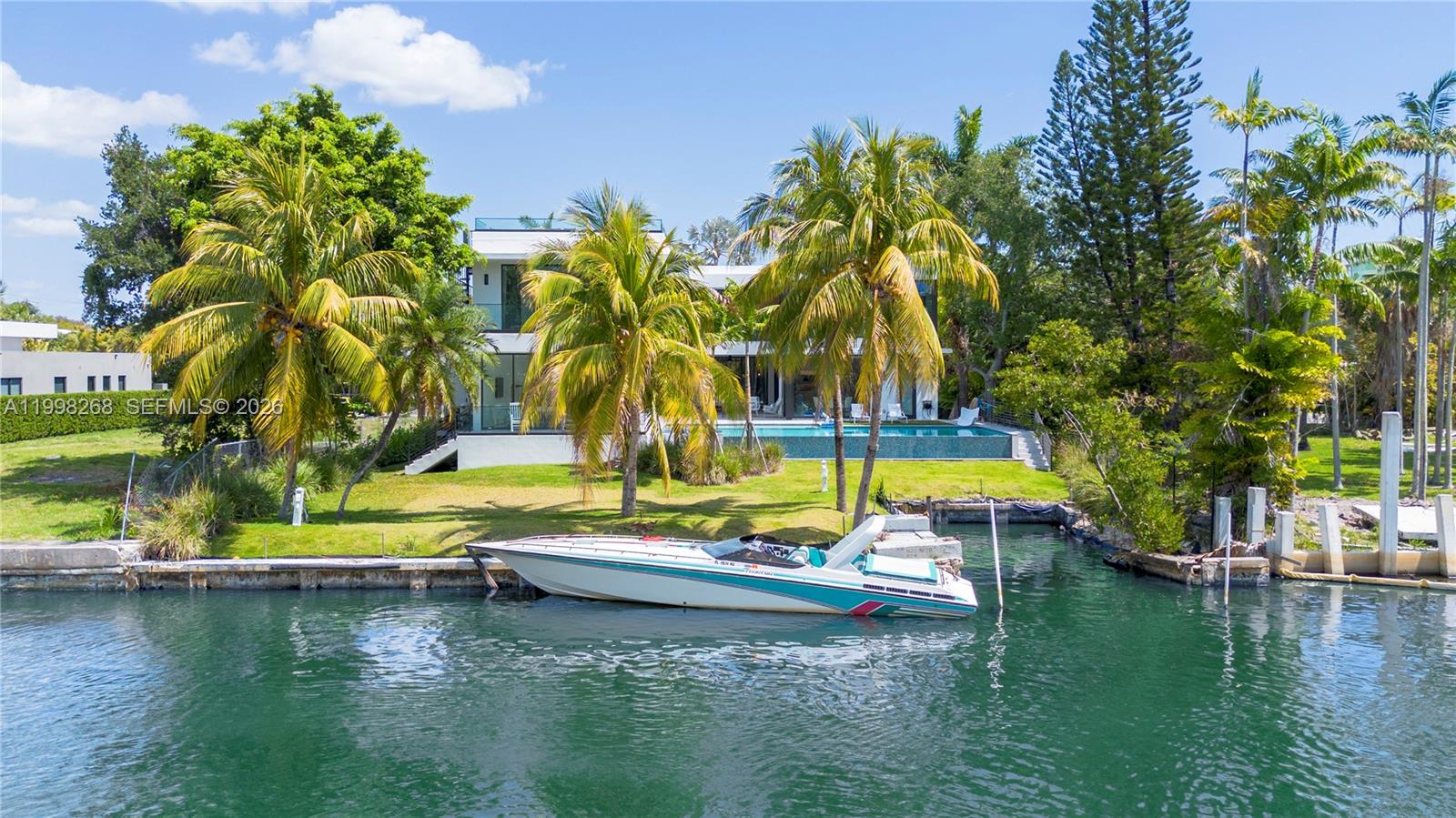 A modern house with a pool and a boat docked on a canal — 922 NE 78th St, Miami FL 33138, MIAMI, FL