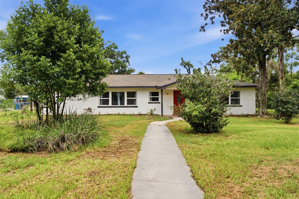 A single-story white house with a red front door and a concrete walkway — 625 LIMONA ROAD, BRANDON, FL