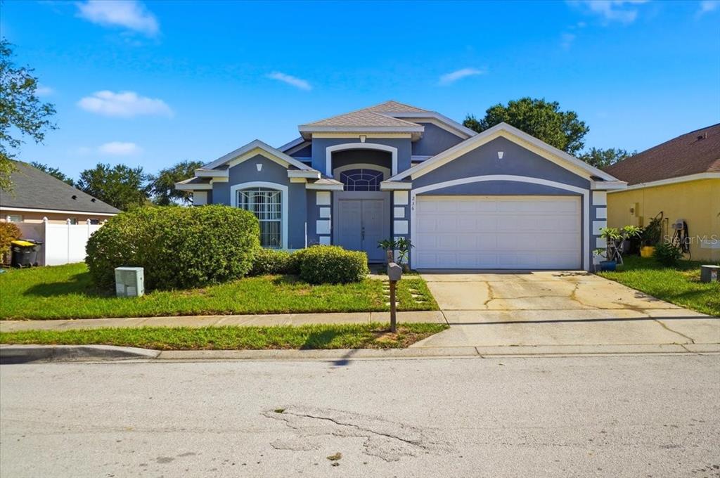A single-story blue house with a two-car garage and a front-facing arched window — 236 SOMERSET DRIVE, DAVENPORT, FL