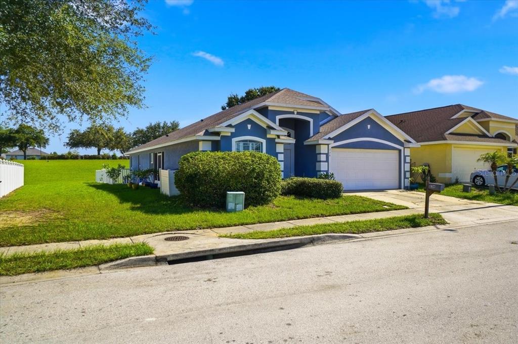 A blue single-story house with a white garage door sits on a grassy corner lot — 236 SOMERSET DRIVE, DAVENPORT, FL