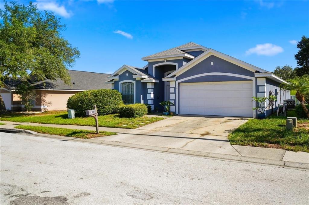 A blue single-story house with a white garage door and a concrete driveway — 236 SOMERSET DRIVE, DAVENPORT, FL