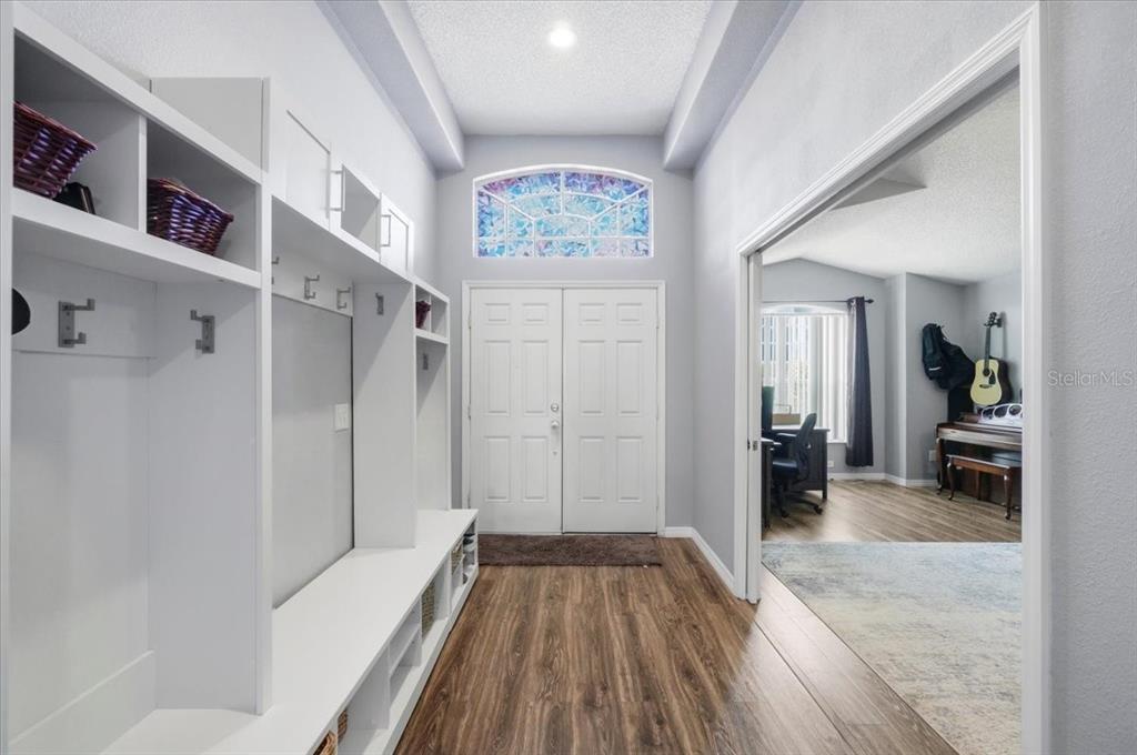 An entryway features a white built-in storage unit, wood-look flooring, and a double front door — 236 SOMERSET DRIVE, DAVENPORT, FL
