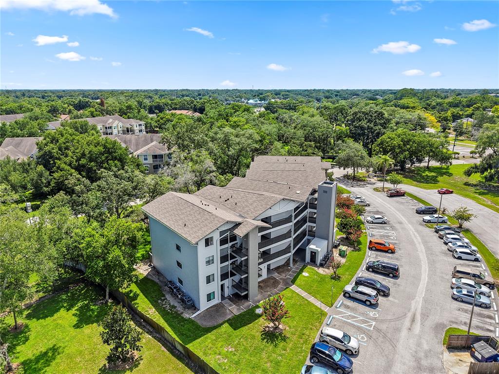 An aerial view shows a multi-story apartment building with a parking lot and surrounding trees — 1036 BONAIRE DRIVE UNIT 2834, ALTAMONTE SPRINGS, FL