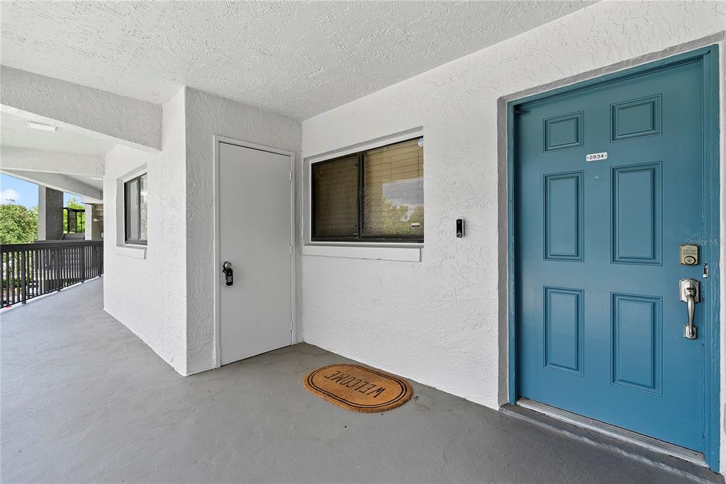 An exterior view of a building entrance featuring a blue front door and white walls — 1036 BONAIRE DRIVE UNIT 2834, ALTAMONTE SPRINGS, FL