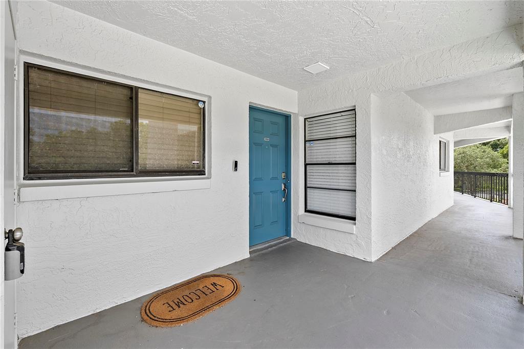 A blue front door sits on a covered concrete porch with two windows — 1036 BONAIRE DRIVE UNIT 2834, ALTAMONTE SPRINGS, FL