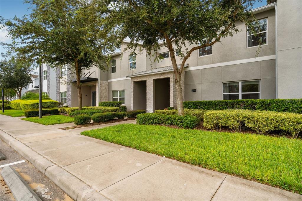 A two-story apartment building exterior features gray stucco walls, stone accents, and manicured landscaping — 590 PEBBLE BEACH DRIVE, DAVENPORT, FL