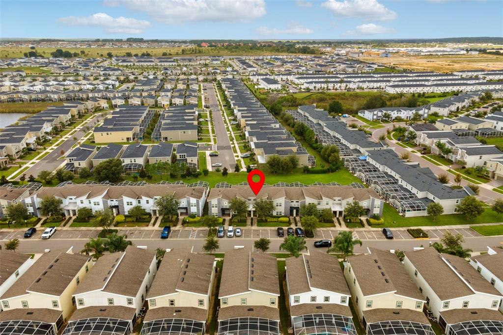An aerial view shows a row of townhouses with a red location pin — 590 PEBBLE BEACH DRIVE, DAVENPORT, FL