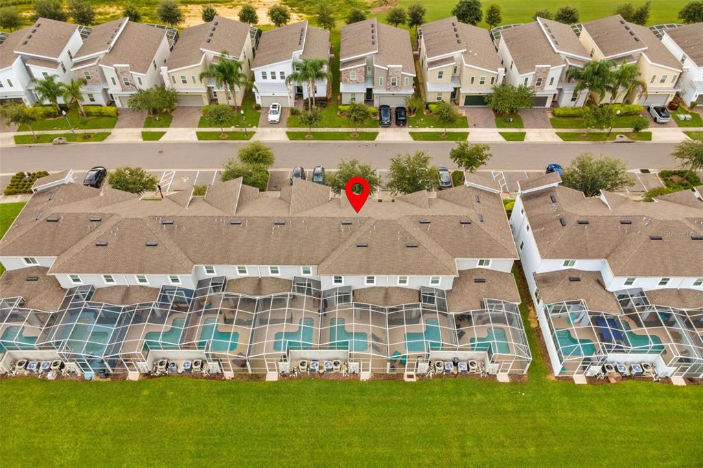 An aerial view shows a row of townhomes with screened-in pools and a grassy backyard — 590 PEBBLE BEACH DRIVE, DAVENPORT, FL