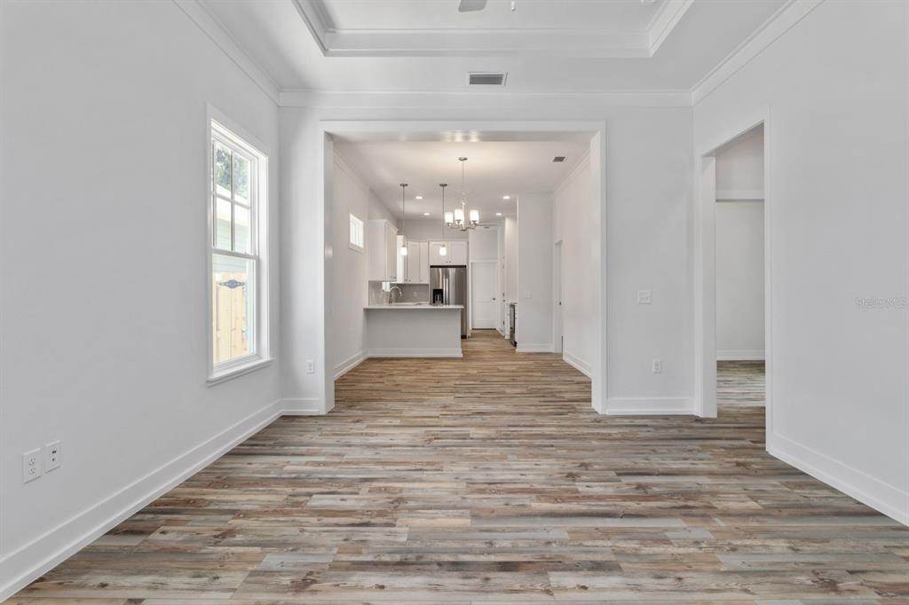 A bright, open-concept room features light wood-look flooring and a view into the kitchen — 420 NW 1ST STREET, GAINESVILLE, FL
