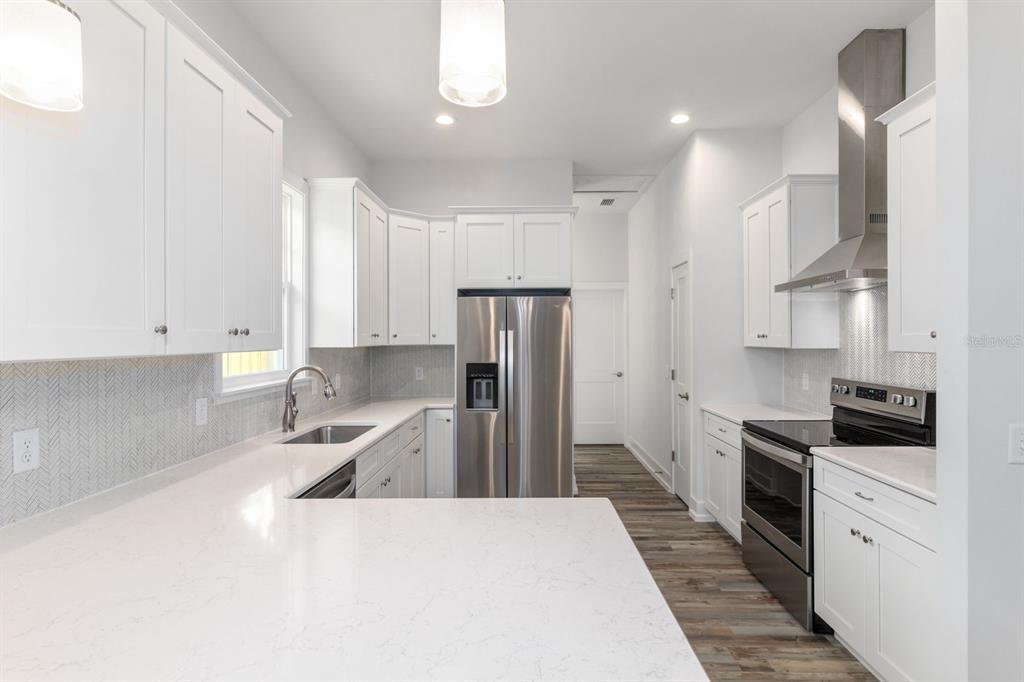 A modern kitchen features white cabinets, stainless steel appliances, and a white quartz countertop — 420 NW 1ST STREET, GAINESVILLE, FL
