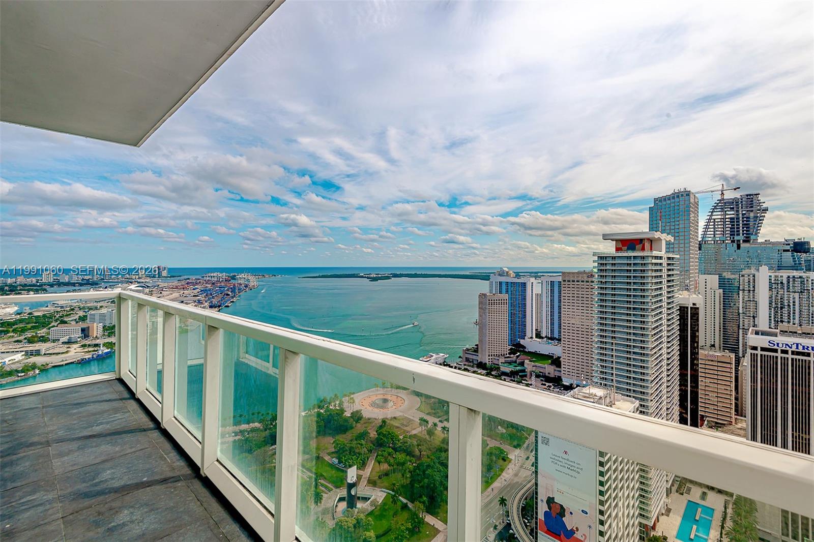 A high-rise balcony overlooks a city skyline, a park, and a large body of water — 244 Biscayne Blvd # 4907, Miami FL 33132, MIAMI, FL