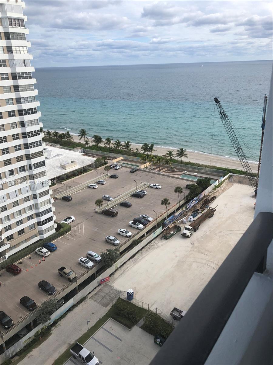An elevated view shows a parking lot, a construction site with a crane, and the ocean — HALLANDALE BEACH, FL