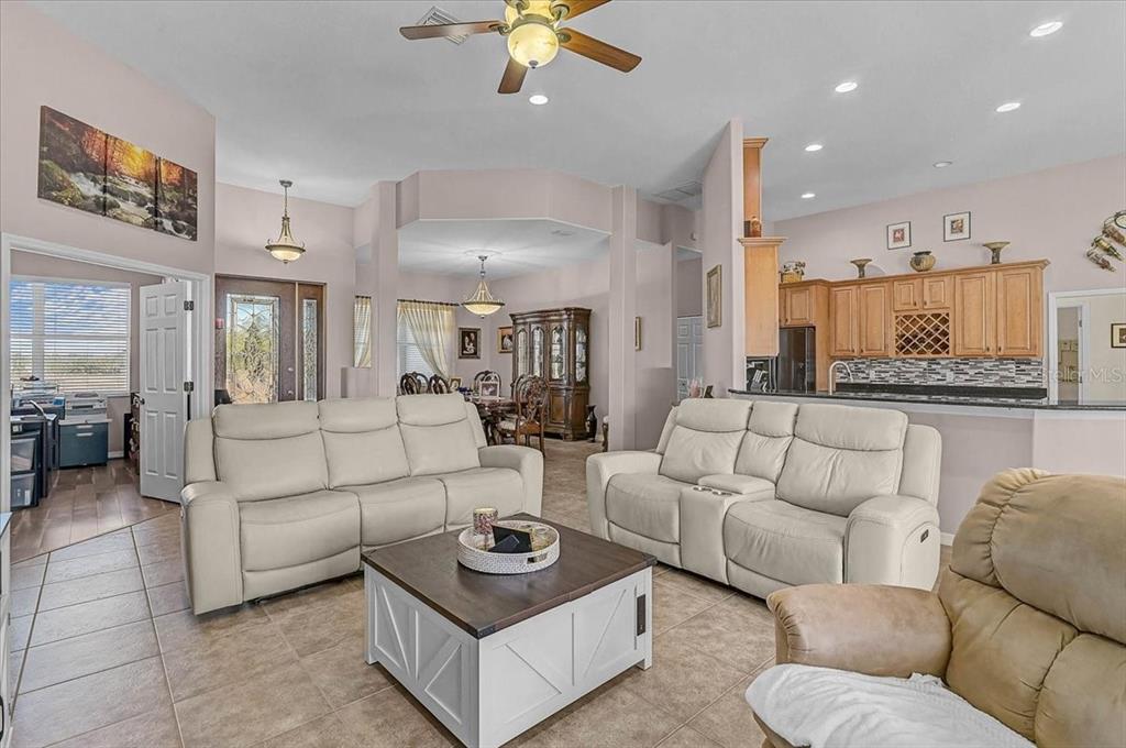 A living room with light-colored sofas, a coffee table, and an open kitchen in back — 25202 E 61ST AVENUE, MYAKKA CITY, FL