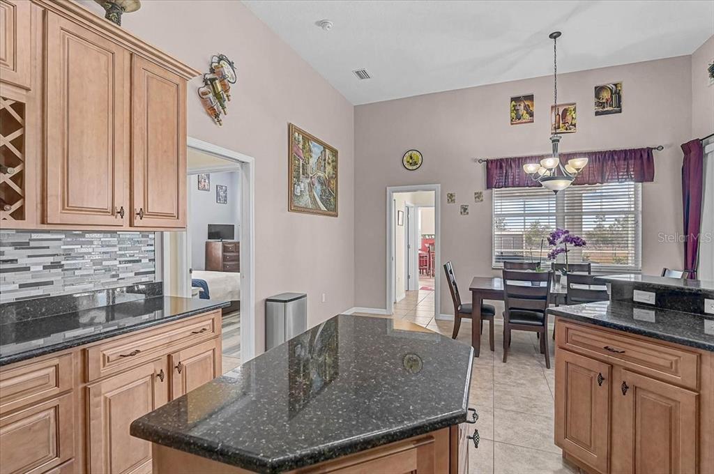 A kitchen with wood cabinets, dark granite countertops, and an adjacent dining area — 25202 E 61ST AVENUE, MYAKKA CITY, FL