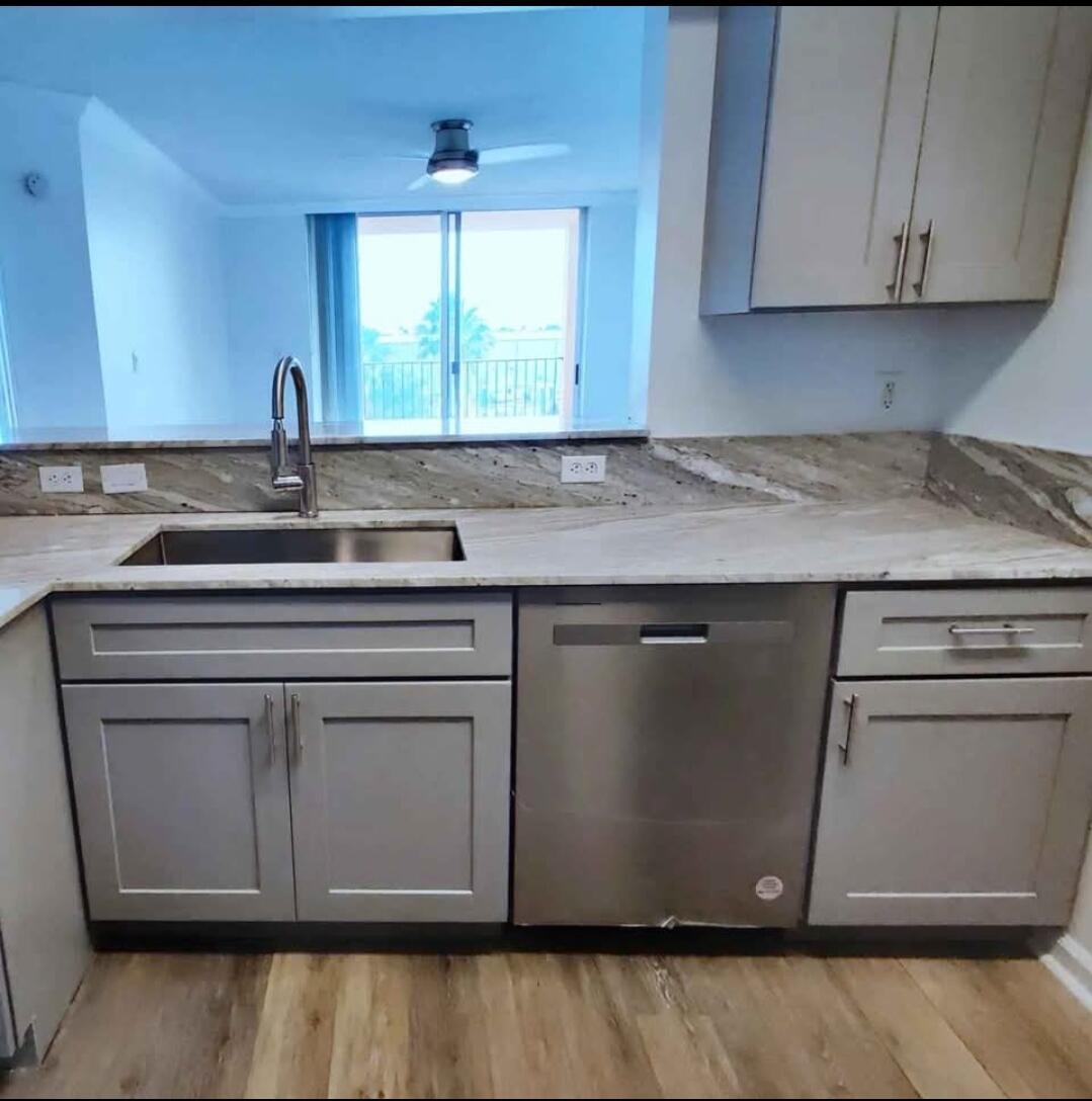 A kitchen with grey cabinets, stainless steel appliances, and stone countertops overlooking a living area — 1000 Scotia Drive # 506, Hypoluxo FL 33462, HYPOLUXO, FL