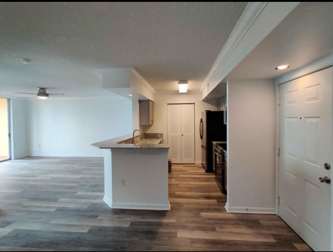 A view from an entryway looking into a kitchen with a breakfast bar and living area — 1000 Scotia Drive # 506, Hypoluxo FL 33462, HYPOLUXO, FL
