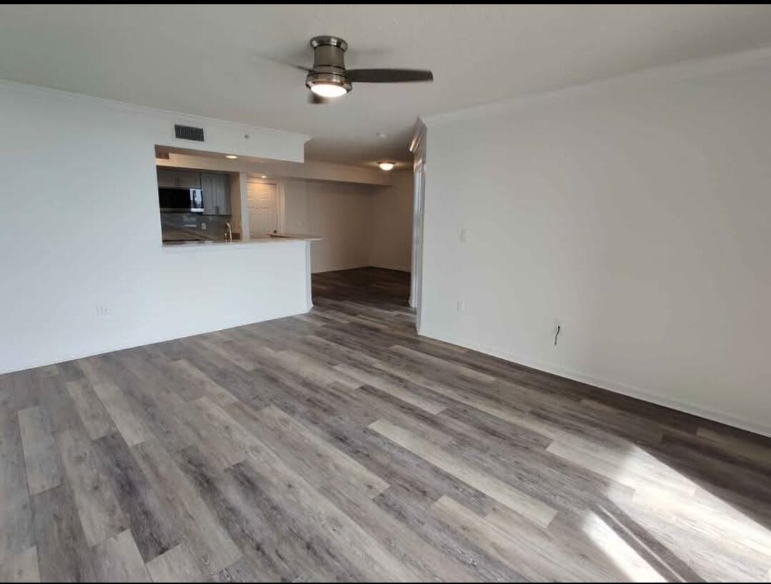 An open-concept living area features light gray wood-look flooring, white walls, and a ceiling fan — 1000 Scotia Drive # 506, Hypoluxo FL 33462, HYPOLUXO, FL