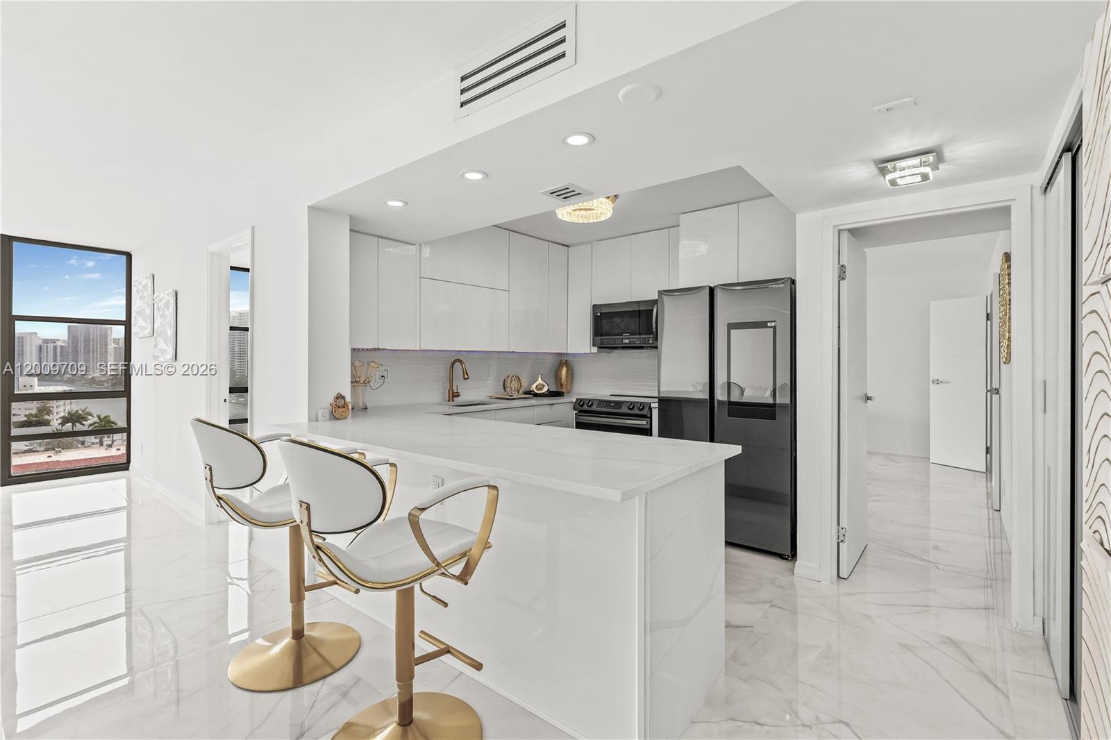A dining area features a white table and chairs set against a large window view — 2017 S Ocean Dr # 1206, Hallandale Beach FL 33009, HALLANDALE BEACH, FL