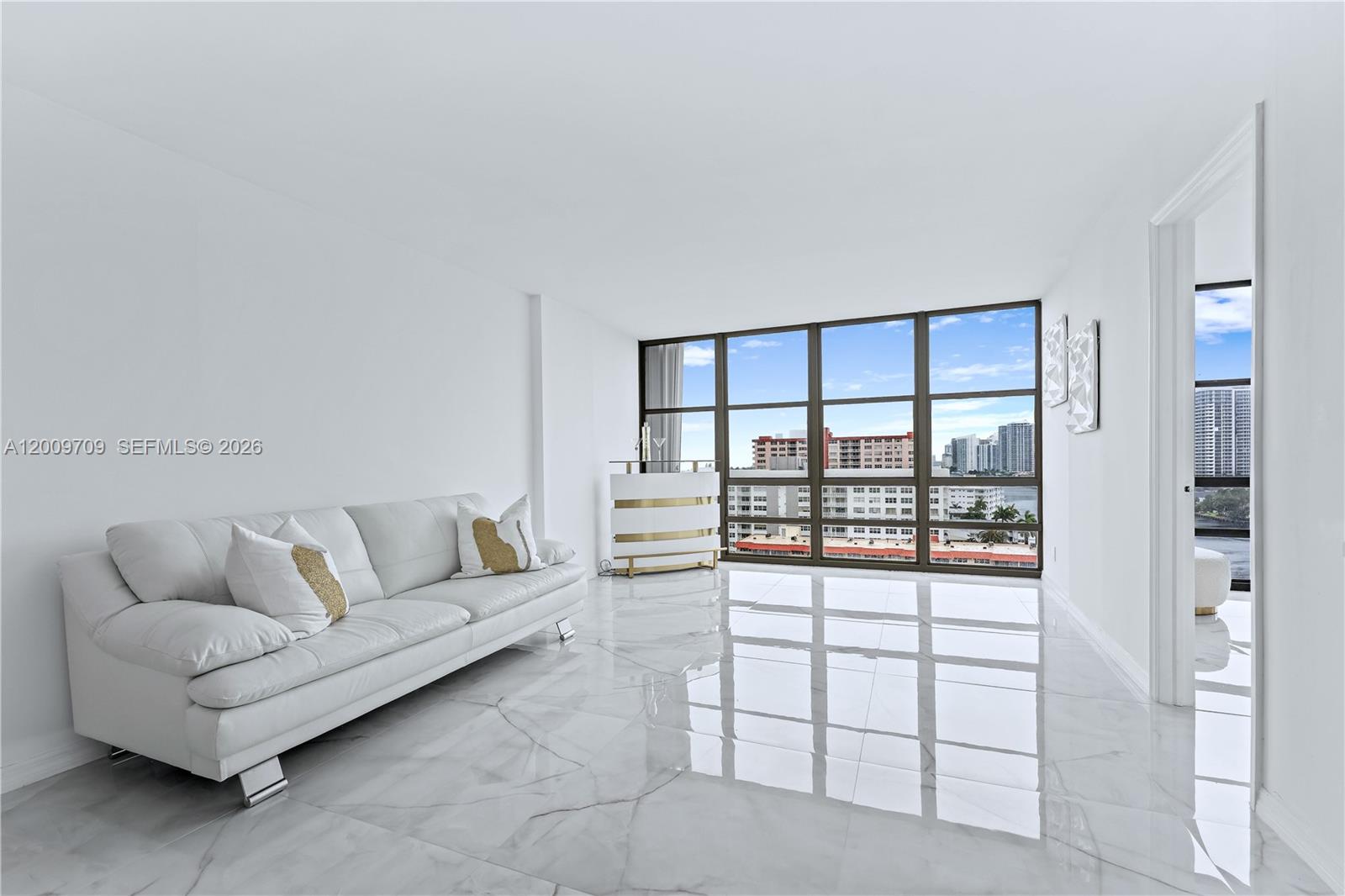 A bright, open-concept living area features white marble floors, a modern kitchen, and floor-to-ceiling windows — 2017 S Ocean Dr # 1206, Hallandale Beach FL 33009, HALLANDALE BEACH, FL