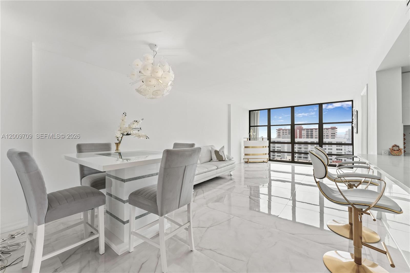 A modern kitchen features white cabinetry, a marble-topped breakfast bar, and stainless steel appliances — 2017 S Ocean Dr # 1206, Hallandale Beach FL 33009, HALLANDALE BEACH, FL