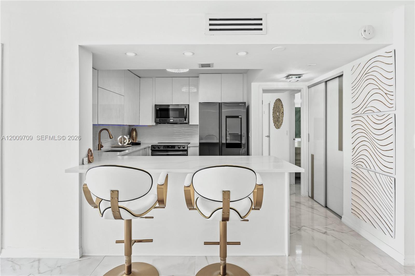 A bright living room features white marble floors, a kitchen bar, and floor-to-ceiling windows — 2017 S Ocean Dr # 1206, Hallandale Beach FL 33009, HALLANDALE BEACH, FL