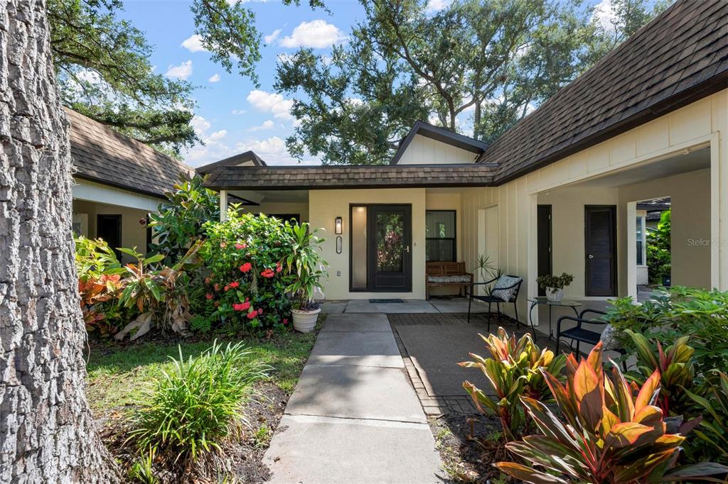 A concrete walkway leads to the front entrance of a house with a covered porch — 2227 CIRCLEWOOD DRIVE UNIT 52, SARASOTA, FL